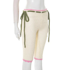 Mannequin wearing a pair of beige crochet pants with green drawstrings and pink trim on a white background.