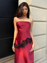 Woman wearing a strapless dress with black lace trim against a building wall.