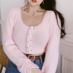 Person wearing a pink cardigan with a neutral background