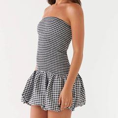 Black and white checkered strapless dress with ruffled hem on a white background