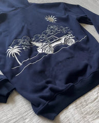 Navy blue sweatshirt with white graphic design of a beach scene featuring a car, palm tree, and sun.