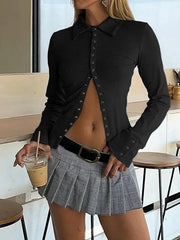 Person wearing a black button-up shirt and gray pleated skirt holding a drink.