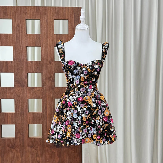Black mini dress with vibrant floral embroidery and sequin straps on a mannequin.