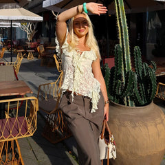 Woman posing outdoors with tables and chairs in the background