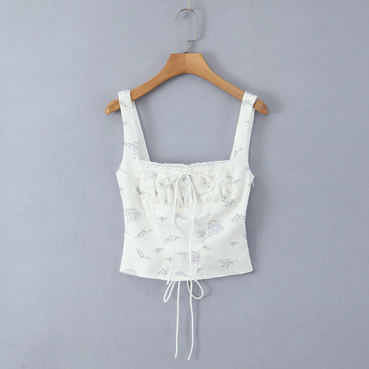White lace crop top on a wooden hanger against a gray background