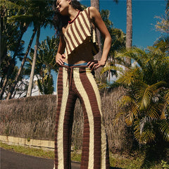 Person wearing a brown and beige striped outfit standing outdoors with palm trees in the background