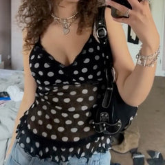 Person wearing a black polka dot top with a blurred background