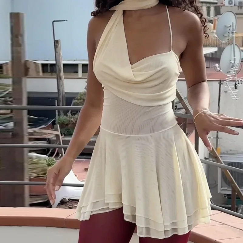 A white mini dress featuring a draped scarf, strappy design, and frill details, shown on model.