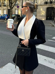 A woman wearing a flattering black blazer dress with a white collar, perfect for a professional or party setting.