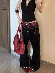 Person wearing a black outfit with red accents, holding a red studded handbag.