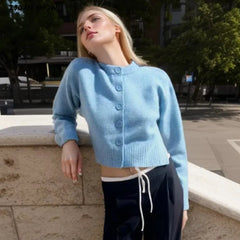 A woman wearing a blue cardigan layered over a white t-shirt and jeans, creating a casual yet chic look.