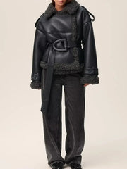 Black leather coat with shearling trim worn by a model on a beige background