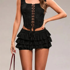 Black lace-up top and ruffled shorts on a neutral background