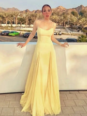 Woman in a yellow dress standing by a pool with mountains in the background