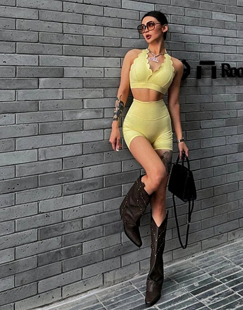 Woman in a neon green outfit with high boots leaning against a gray brick wall.