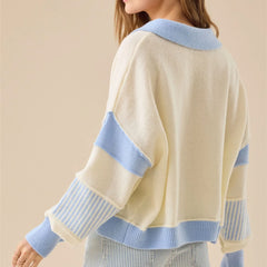 Beige sweater with blue accents worn by a person on a beige background
