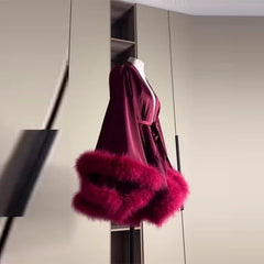 Mannequin wearing a burgundy dress with pink fur trim against a neutral background