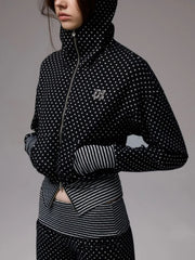Person wearing a black and white polka dot jacket with a gray background