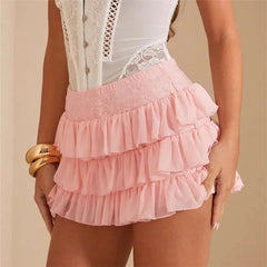 Person wearing a white lace top and pink ruffled skirt on a beige background