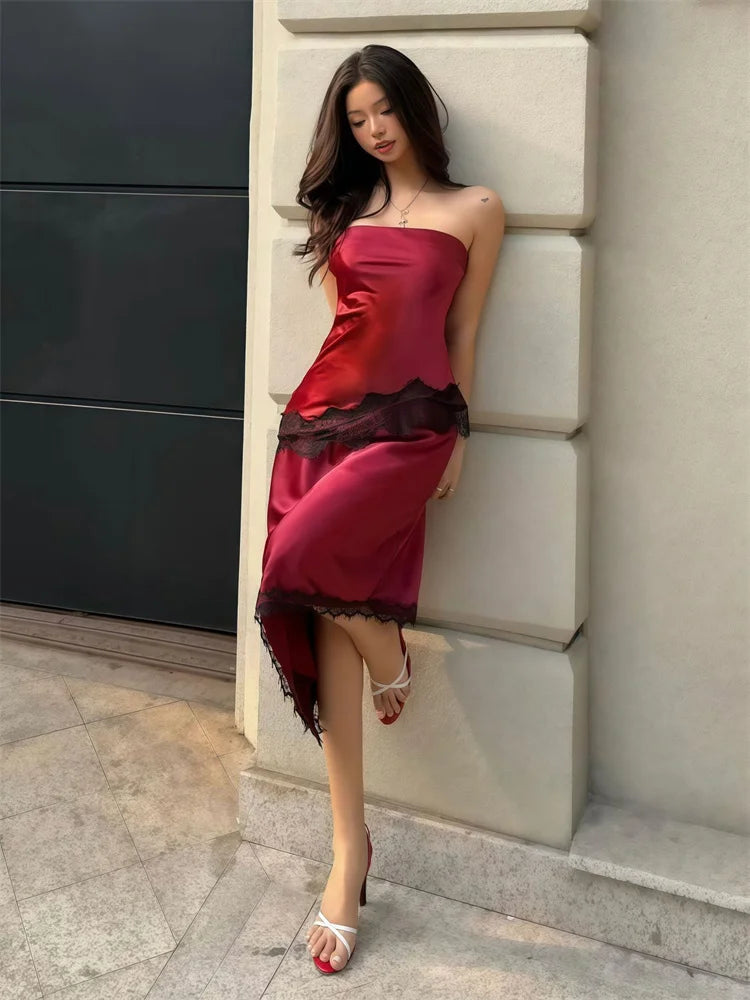 Woman in a burgundy dress leaning against a wall.