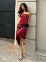 Woman in a burgundy dress leaning against a wall.