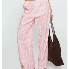 Person wearing pink striped pants holding a brown bag on a light gray background