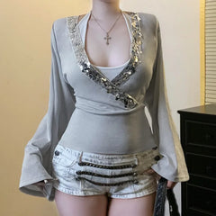 Mannequin wearing a gray top with embellishments and white shorts against a plain background