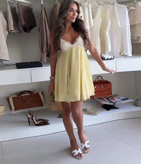 Woman in a yellow dress standing in a clothing store with racks of clothes and bags in the background.