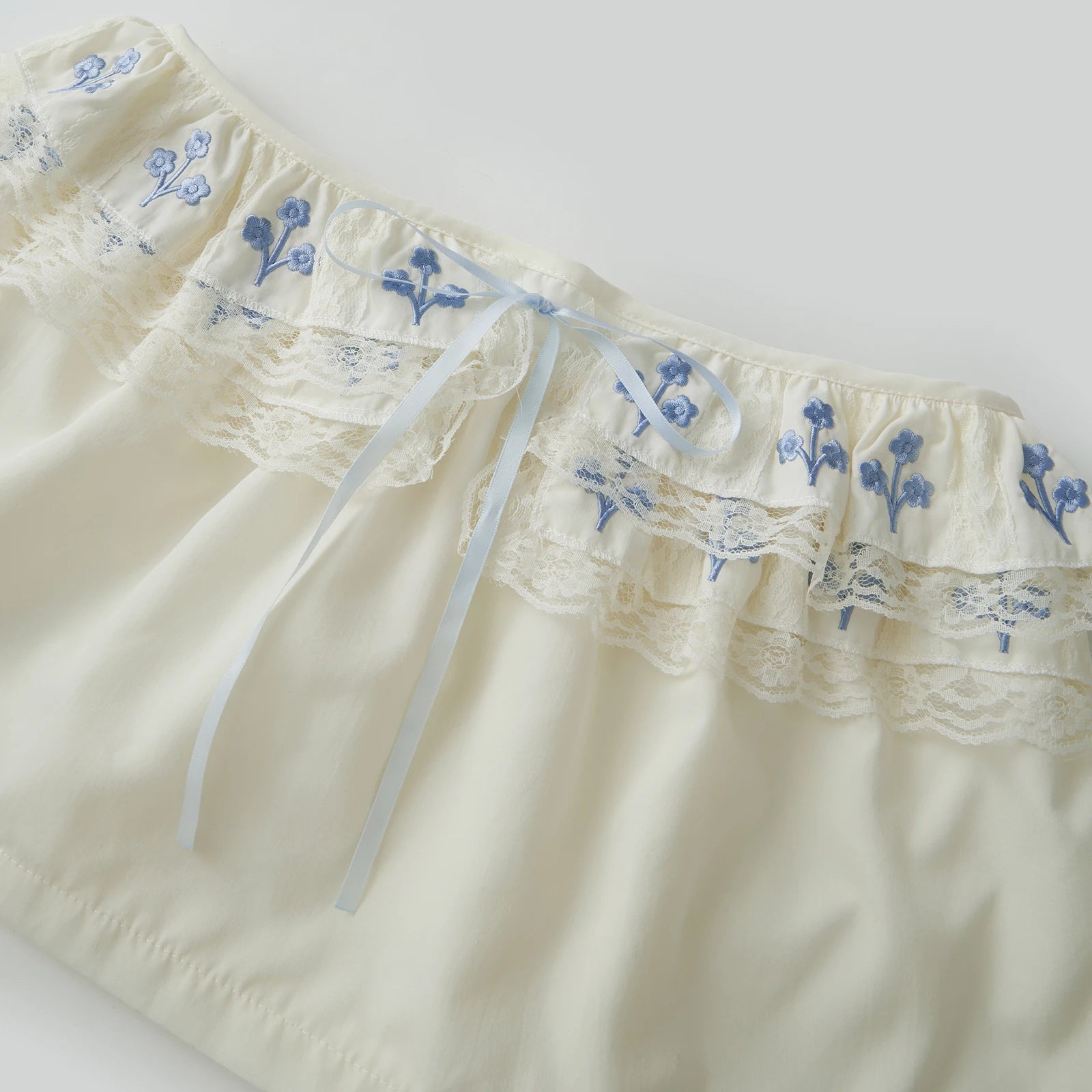 Cream-colored shorts with blue floral embroidery 