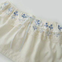 Cream-colored shorts with blue floral embroidery 