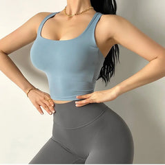 Person wearing a light blue sports bra and gray leggings on a plain background
