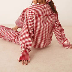 Person wearing a red and white checkered outfit sitting on a beige surface.