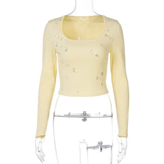 Yellow long-sleeve top with bead embellishments on a mannequin against a white background