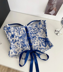 Blue and white floral patterned garment with a blue ribbon on a white surface.