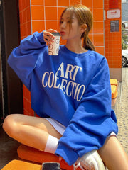 Person wearing a blue sweatshirt with 'ART COLLECTION' text, sitting on an orange chair.