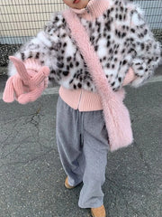 Person wearing a leopard print coat with pink fur trim, pink sweater, gray pants, and brown shoes on a street.
