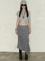 Person wearing a gray outfit with a skirt and crop top against a plain background