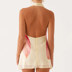 Back view of a person wearing a cream-colored dress with a red and pink abstract pattern 