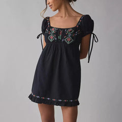 Black dress with floral embroidery on a gray background