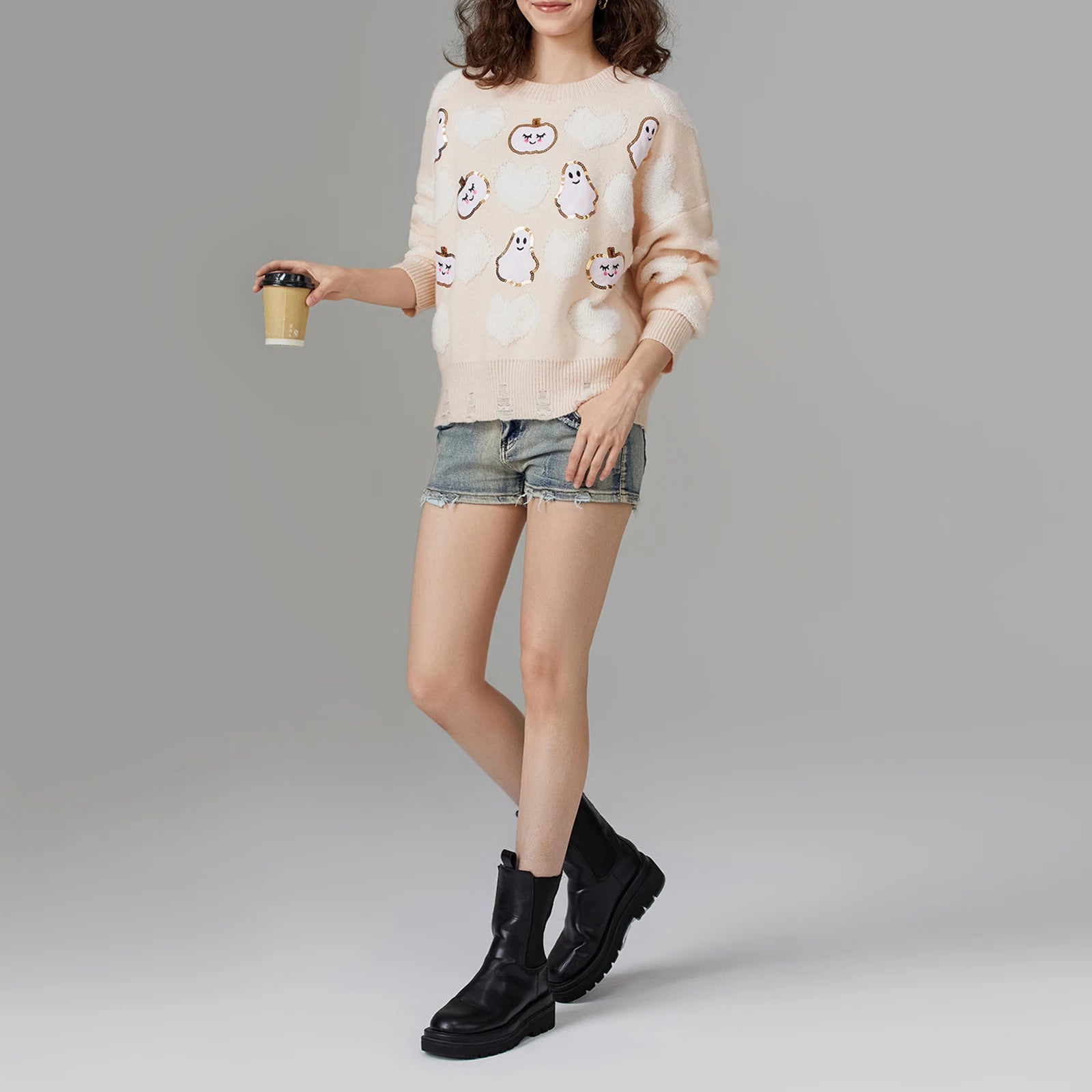 Person wearing a patterned sweater, denim shorts, and black boots 