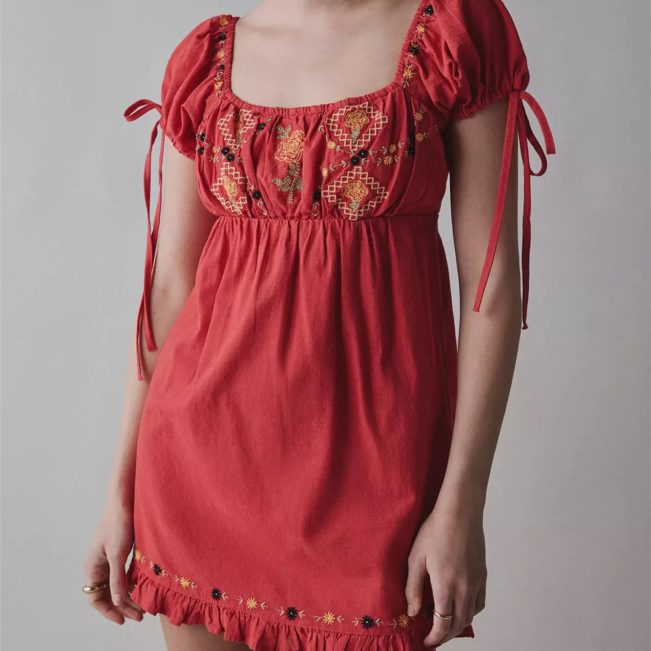 Red dress with embroidery and tied sleeves on a gray background
