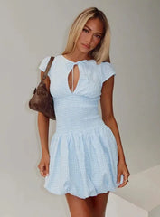 Woman wearing a light blue dress with a plain background