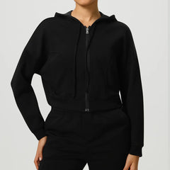 Person wearing a black zip-up hoodie and pants on a light gray background