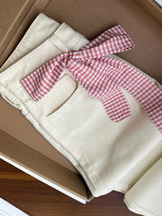 jeans with a red and white checkered bow on a cardboard surface