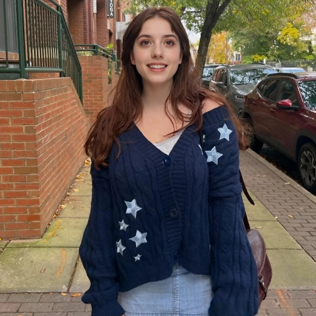 Woman wearing a navy blue cardigan with star patterns on a sidewalk.