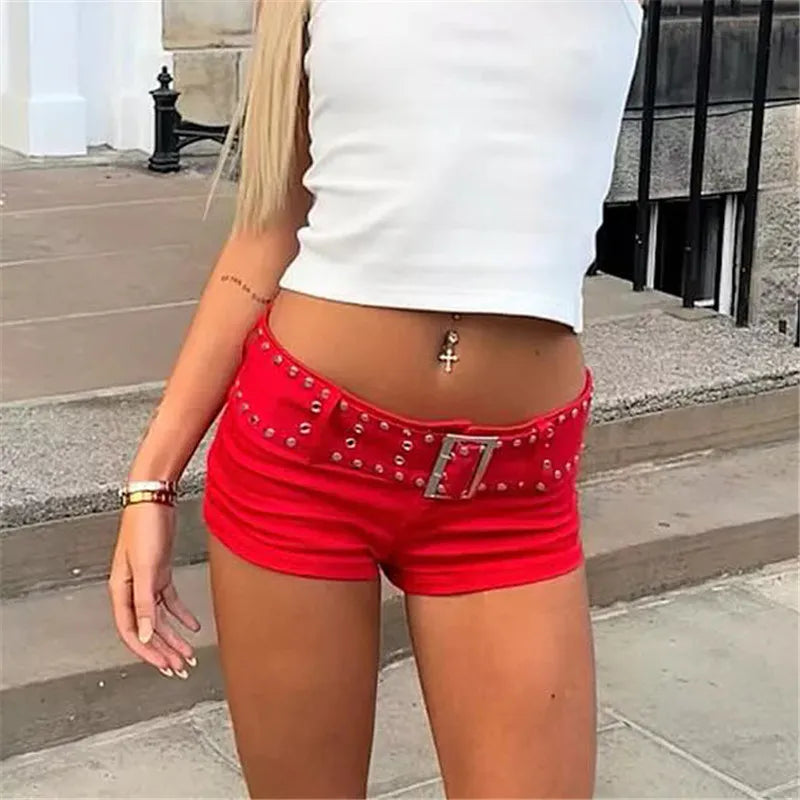 Person wearing red shorts with a studded belt and white top outdoors.