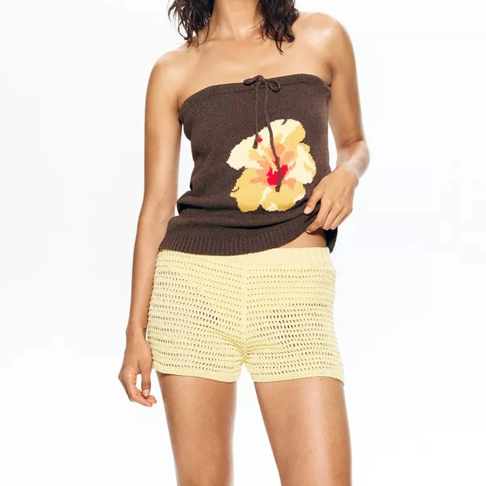 Woman wearing a brown strapless top with a floral design and yellow shorts 
