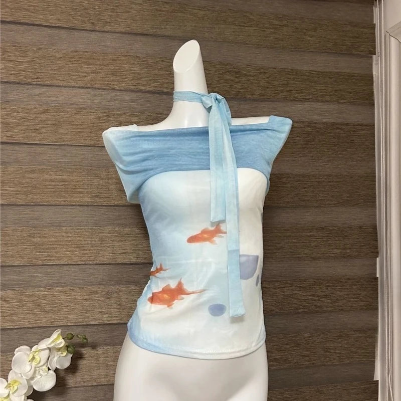 Mannequin wearing a blue and white top with fish design against a wooden panel background