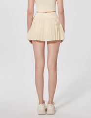 Person wearing a light yellow pleated skirt - back view
