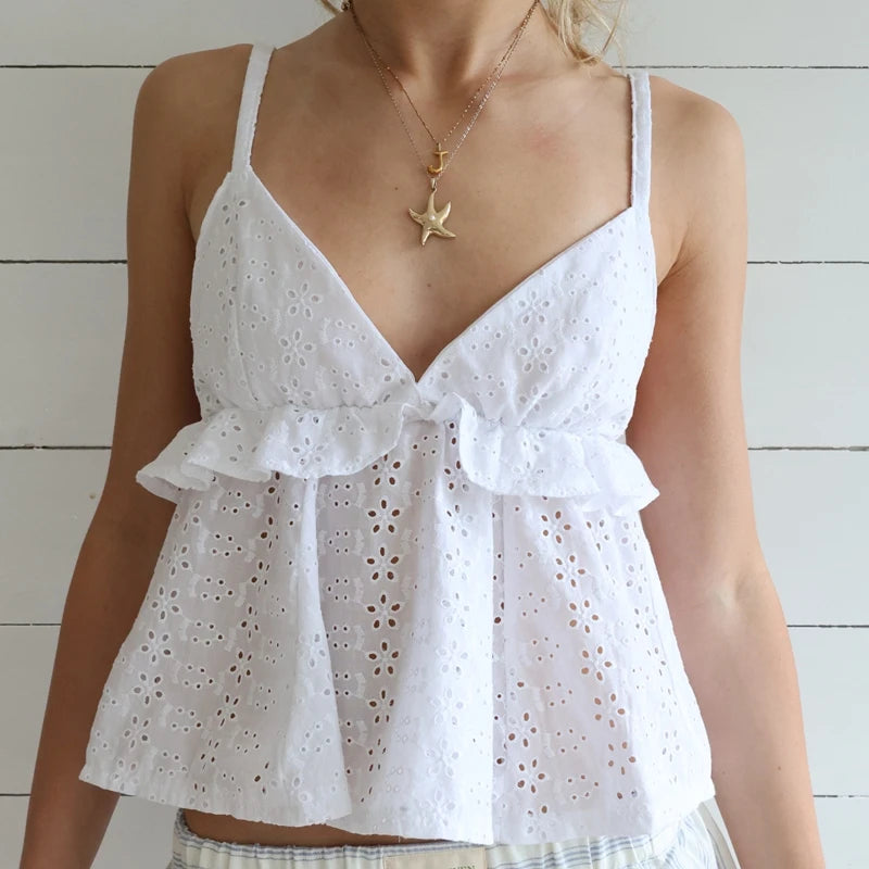 White eyelet top worn by a person with a star-shaped necklace against a white wooden background